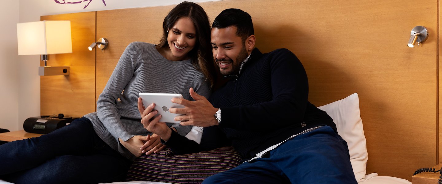 A man and woman sitting together on a bed at BH Parque 93