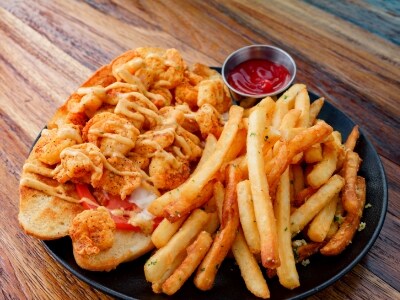 A plate of food with shrimp, fries, and ketchup on a wooden table.