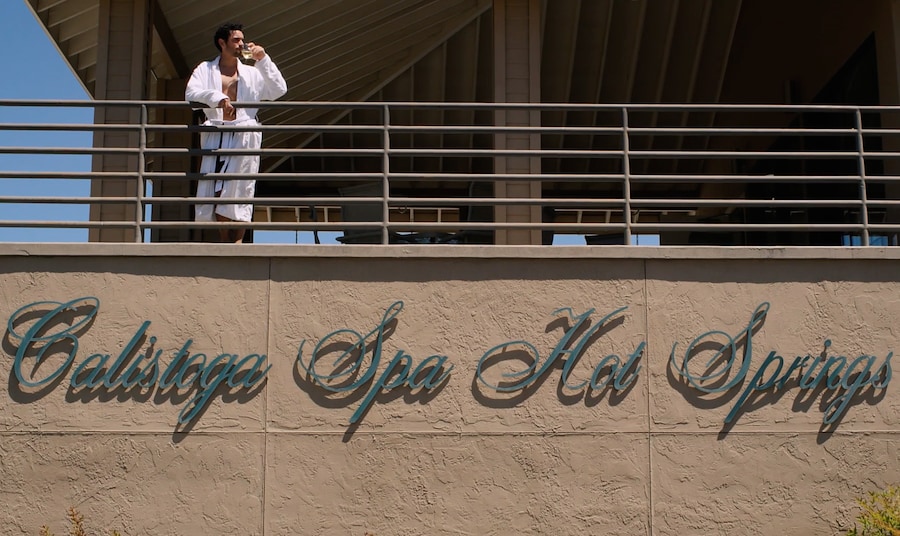 A man drinking from a glass on a balcony