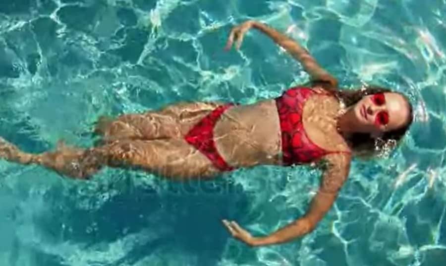 A woman in a red garment floating in a pool