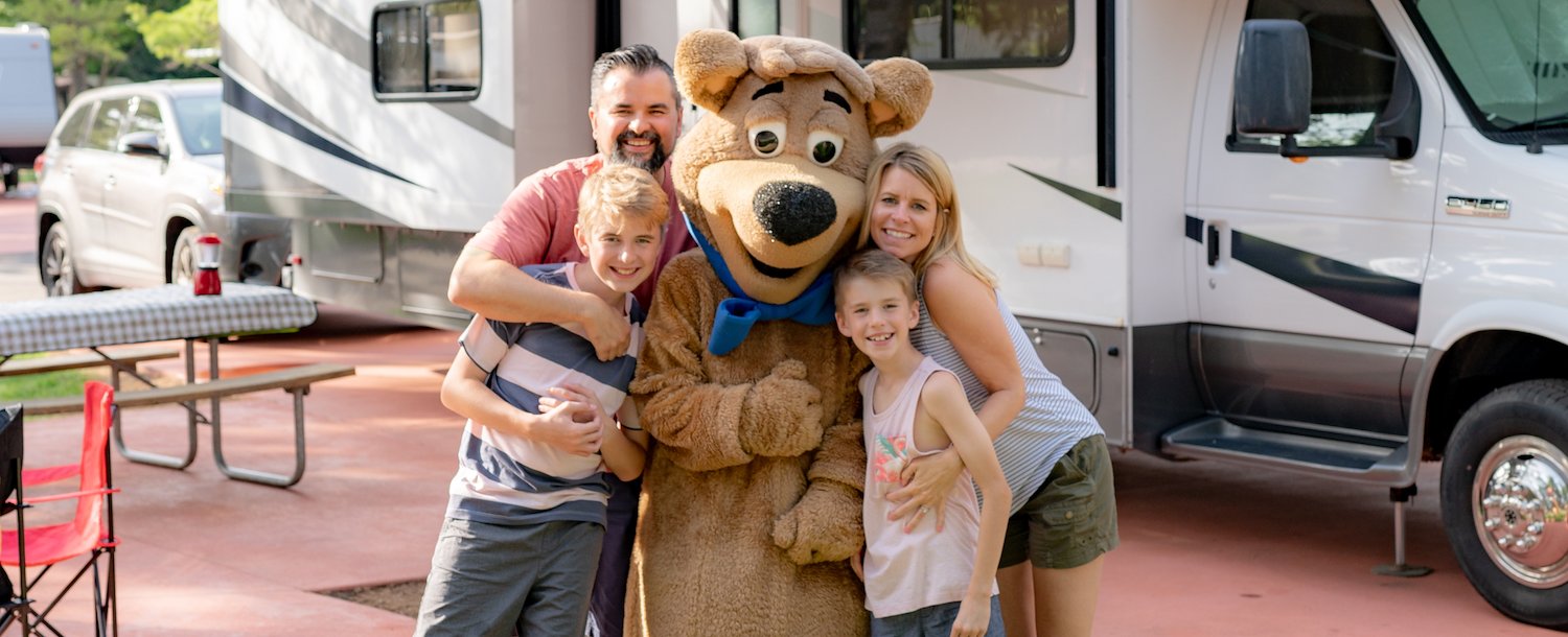 A group of people standing with Yogi Bear at Jellystone Park™ Williamsburg