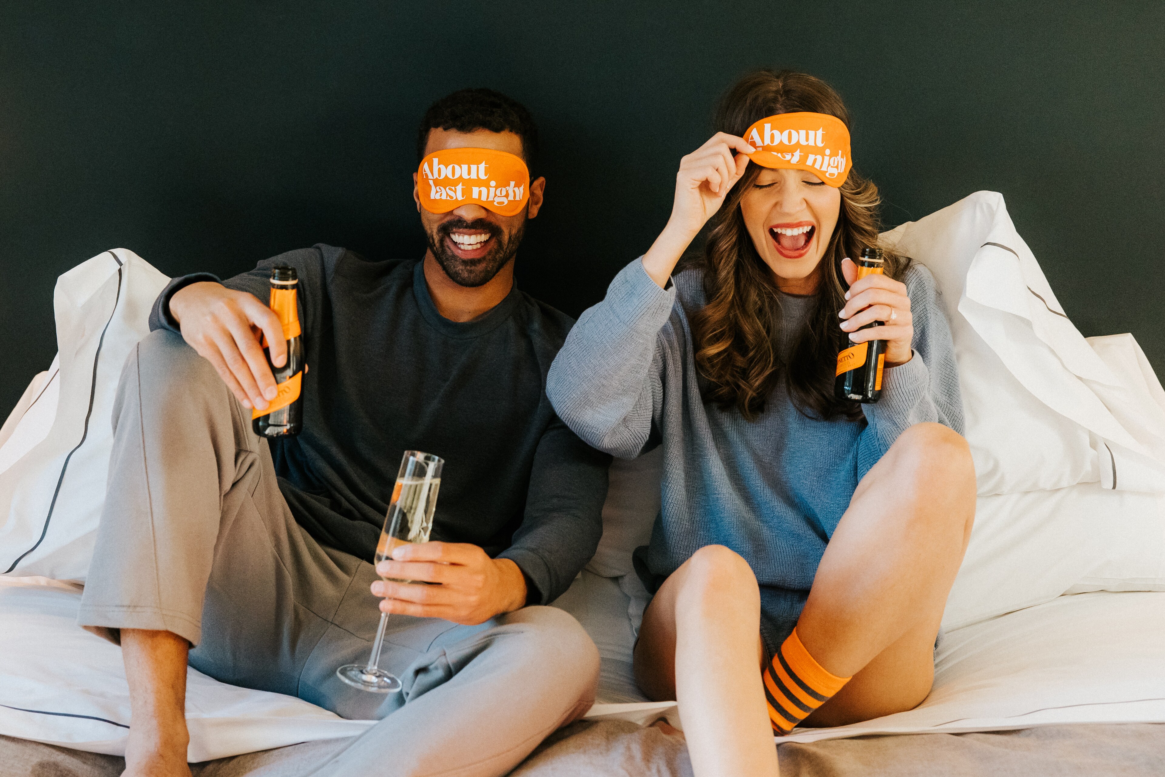A couple enjoys drinks and laughter in their room at Canopy by Hilton Boston Downtown