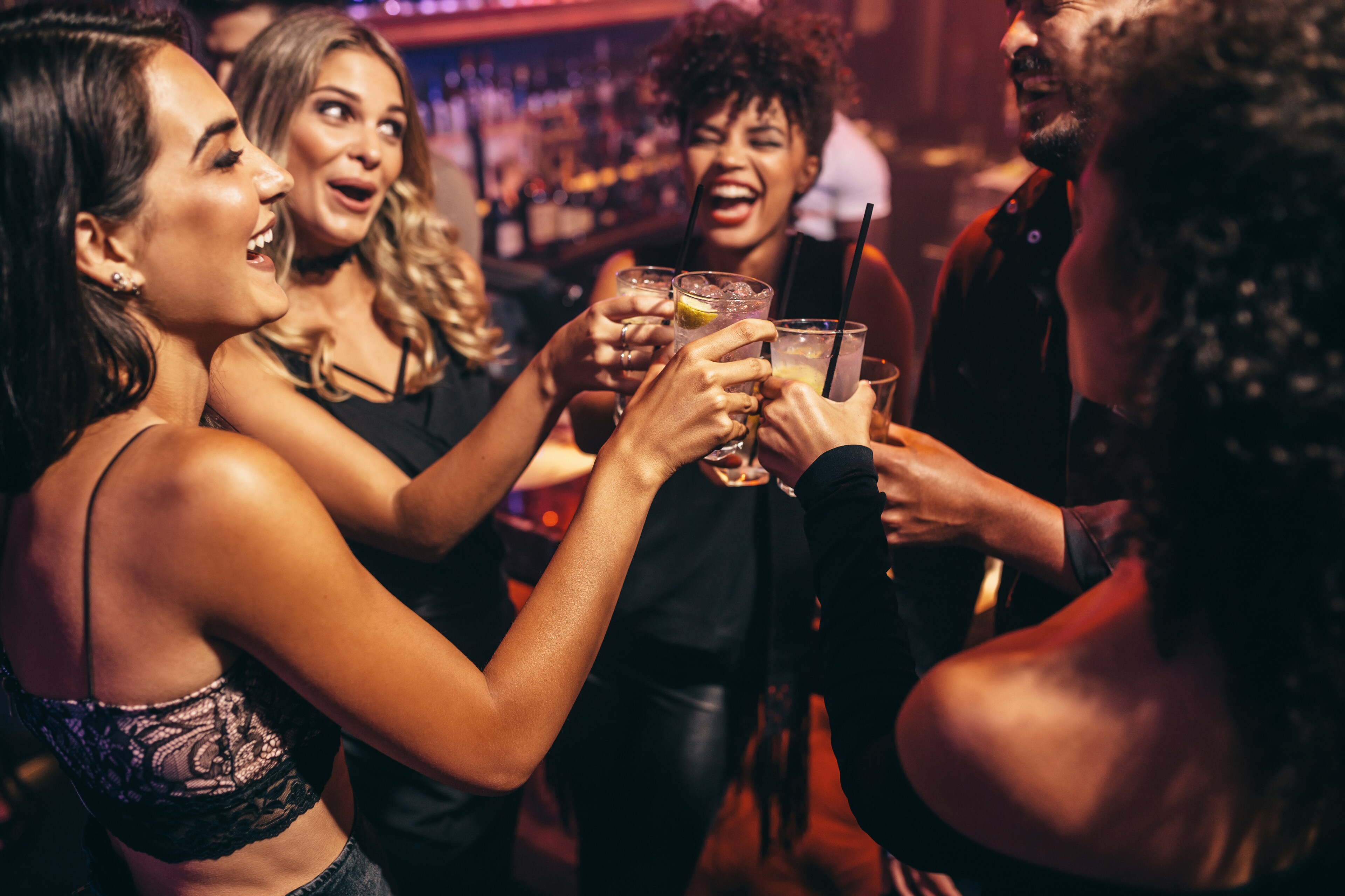 Friends toasting drinks at a lively Boston nightlife venue, enjoying an evening out in Boston, MA.