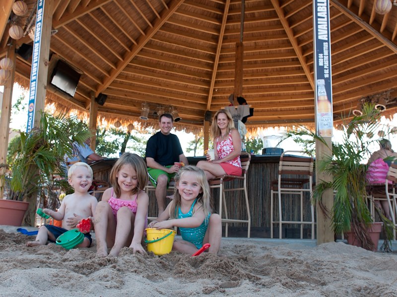 A group of children playing in sand under a gazebo