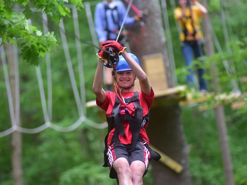 A boy in a helmet and harness on a rope trail