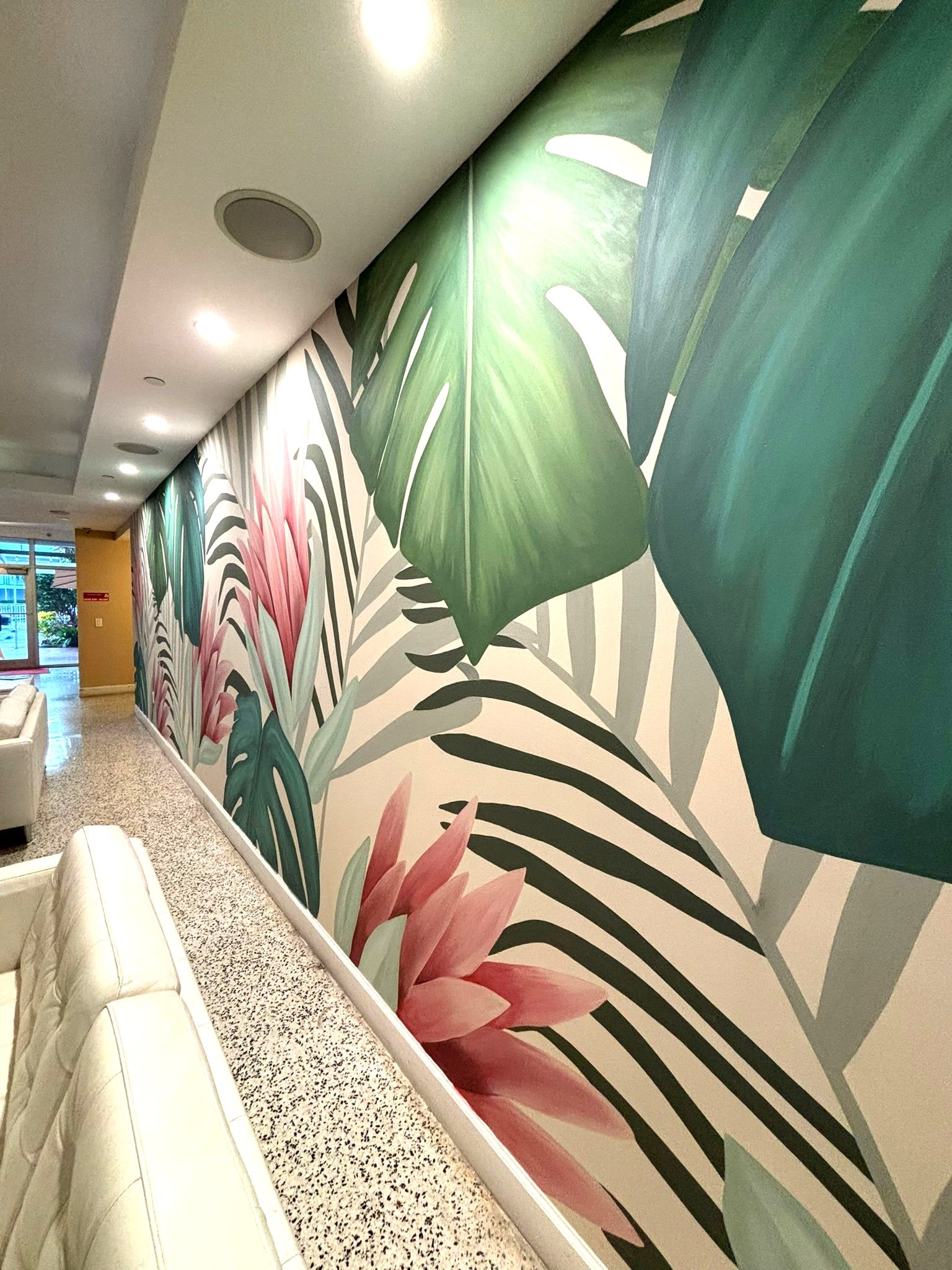 a lobby with a tropical wallpaper and white furniture