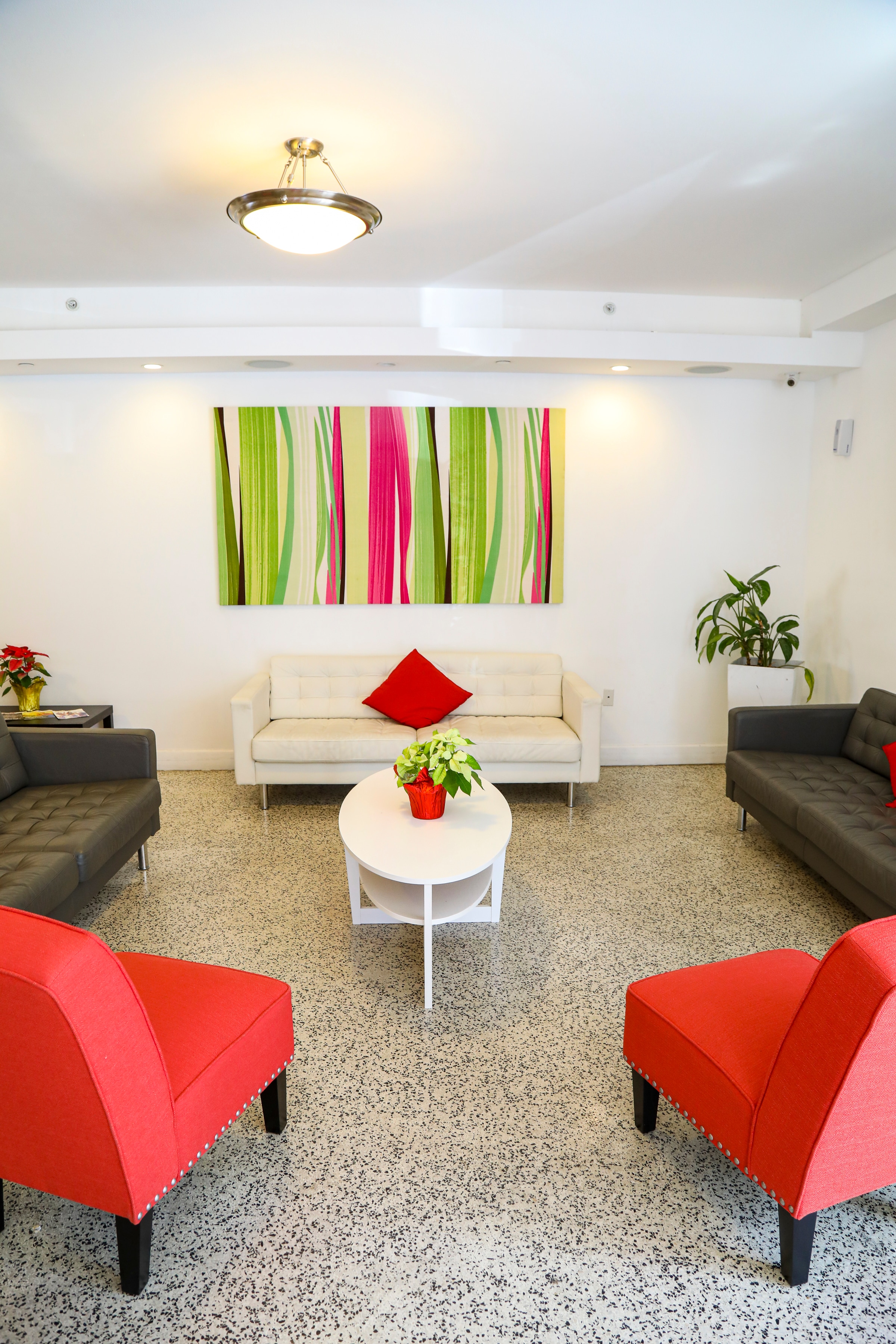 A modern lobby with a white couch, gray sofas, a coffee table, and a large colorful artwork on the wall.