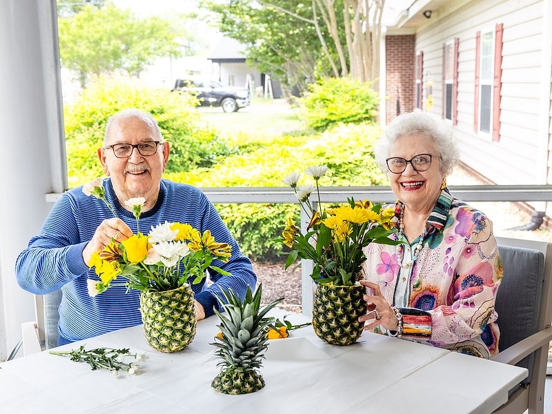 A man and woman sitting at a table with pineapples and flowers