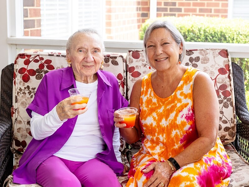 Two women sitting on a couch holding drinks