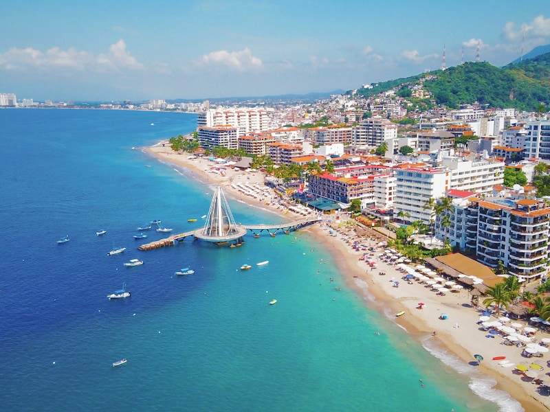 A beach with buildings and boats on the water