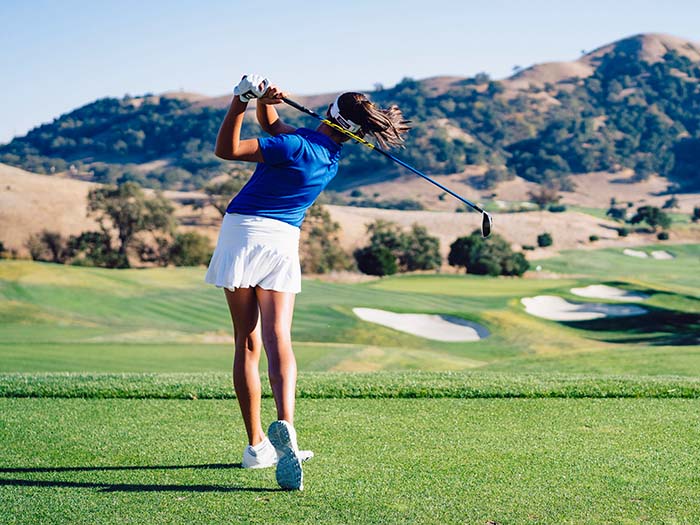 A woman swinging a golf club