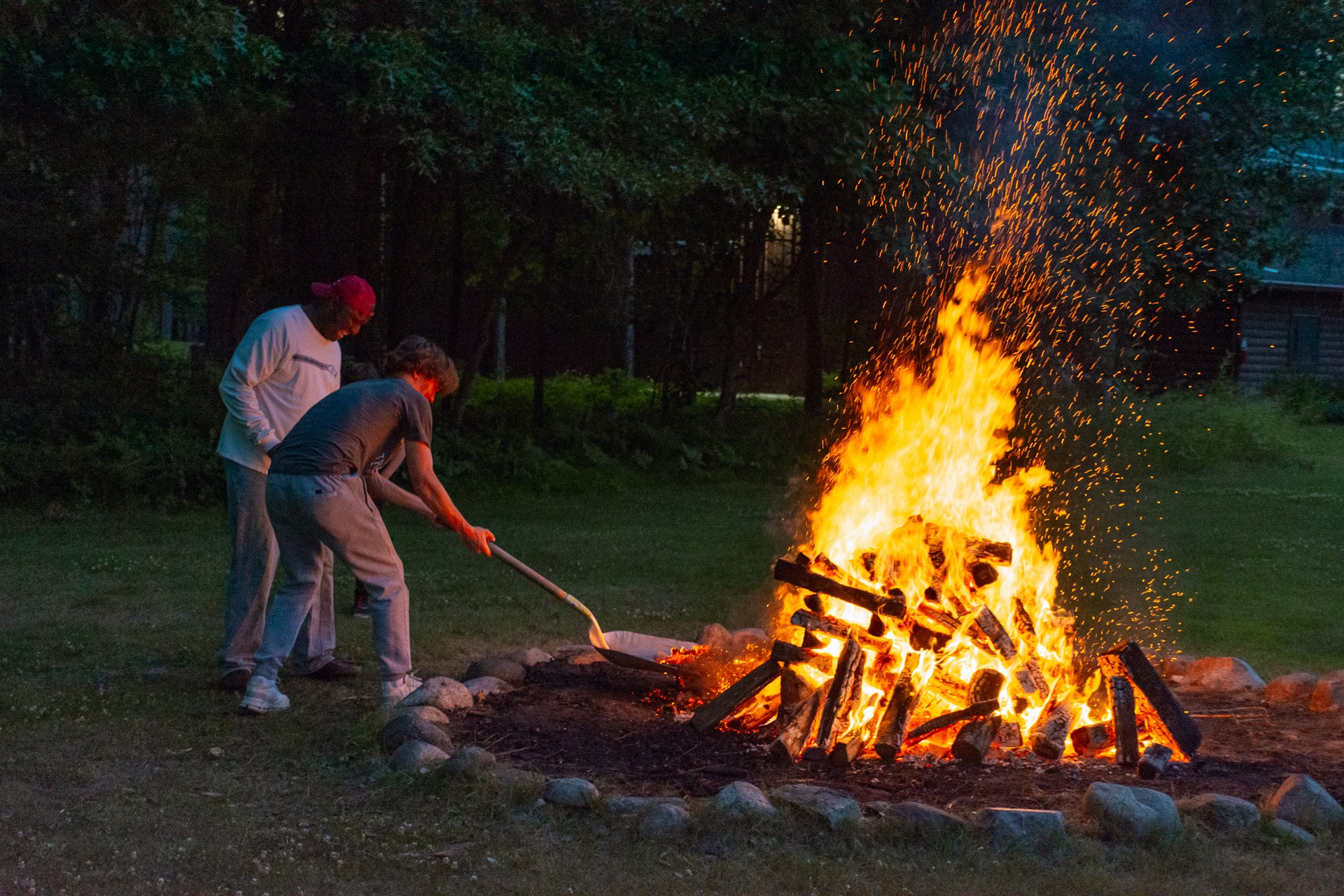 Two men standing around a fire