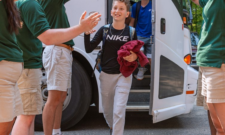 A group of people waving to a boy in a bus