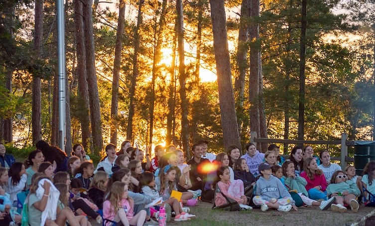 A group of people sitting on the ground in the woods
