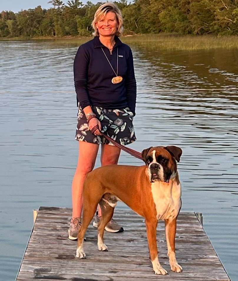 A woman standing on a dock with a dog