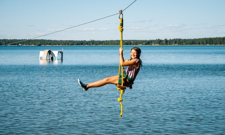 A girl swinging on a rope over water