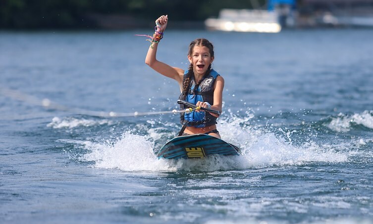A girl in a life jacket on a wakeboard