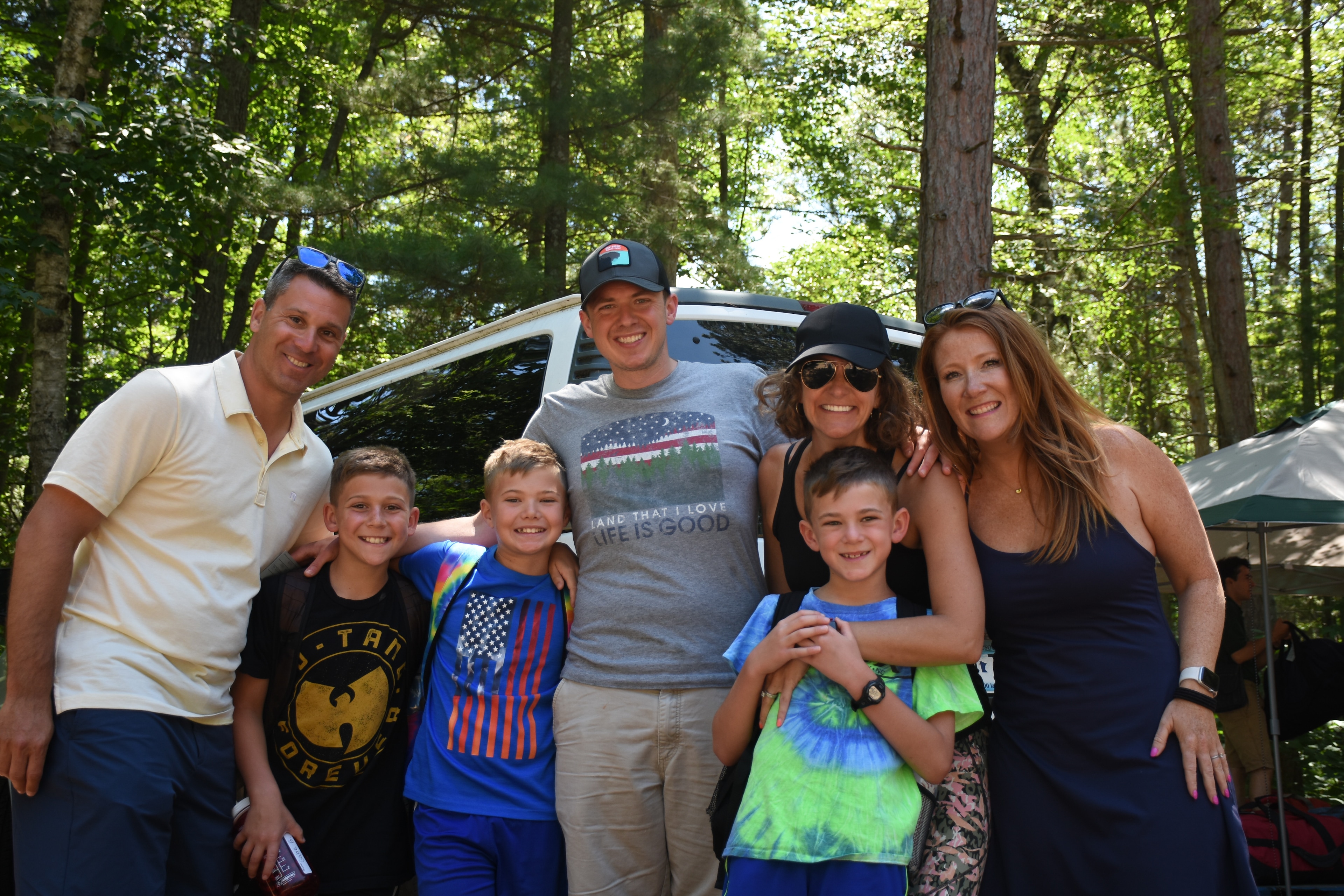 A group of people posing for a photo in front of a white van