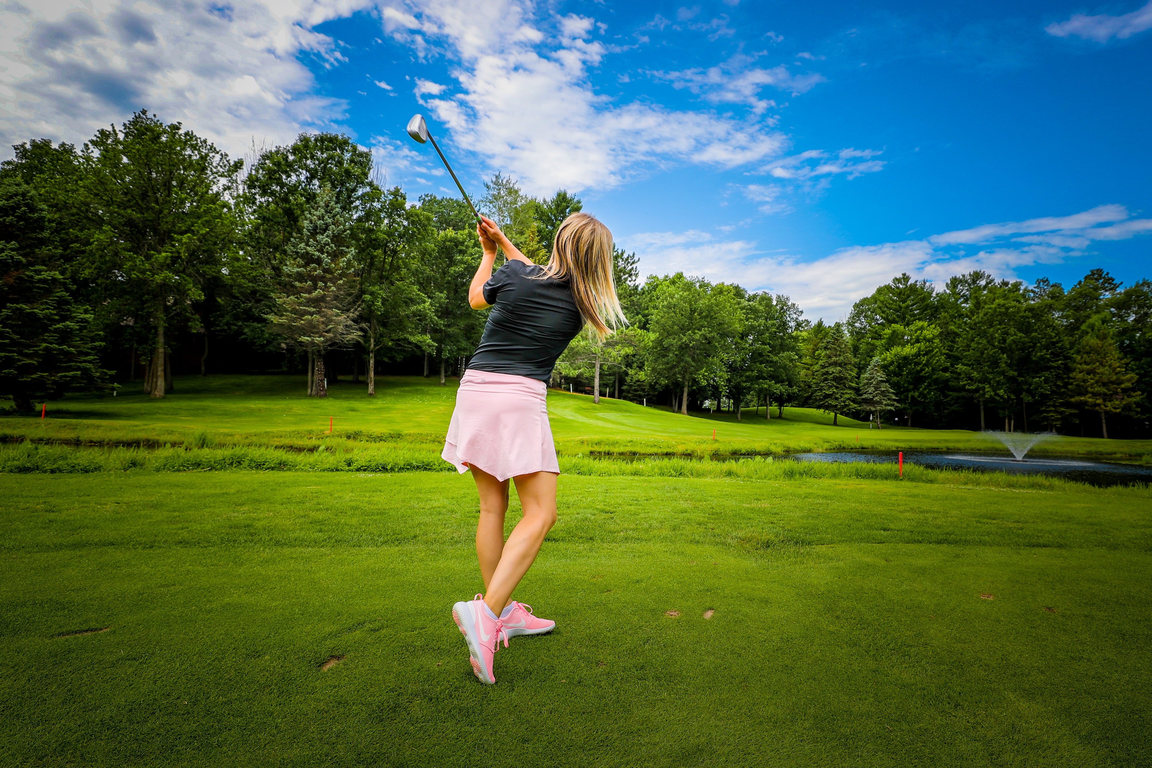 A woman swinging a golf club at The Preserve Golf Course