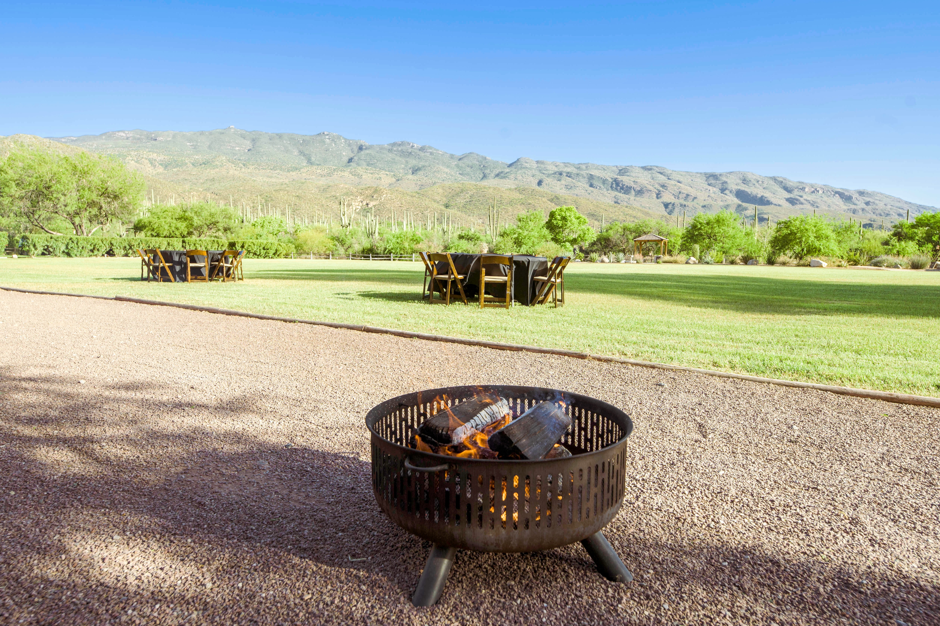 A fire pit in a gravel area with outdoor seating and a mountain view.