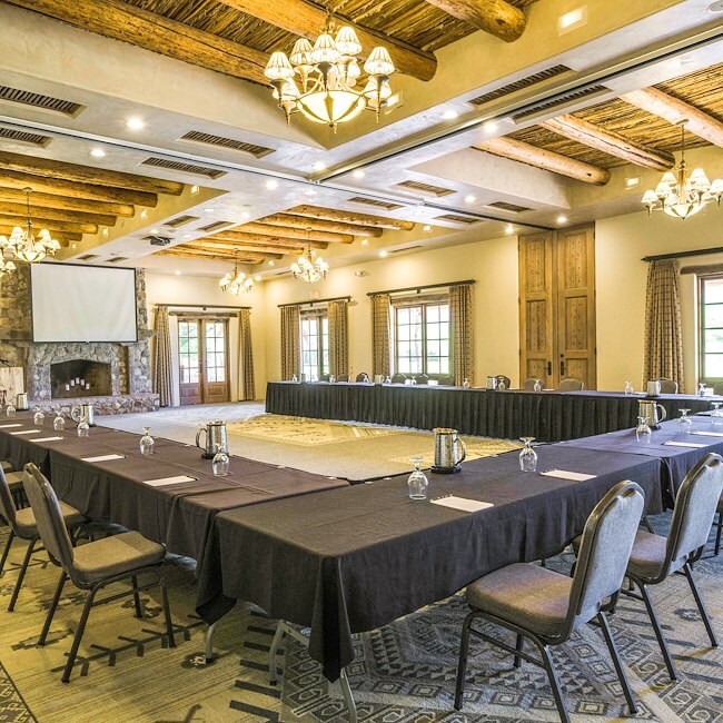 A large meeting room with a long table, chairs, fireplace, and projector screen.