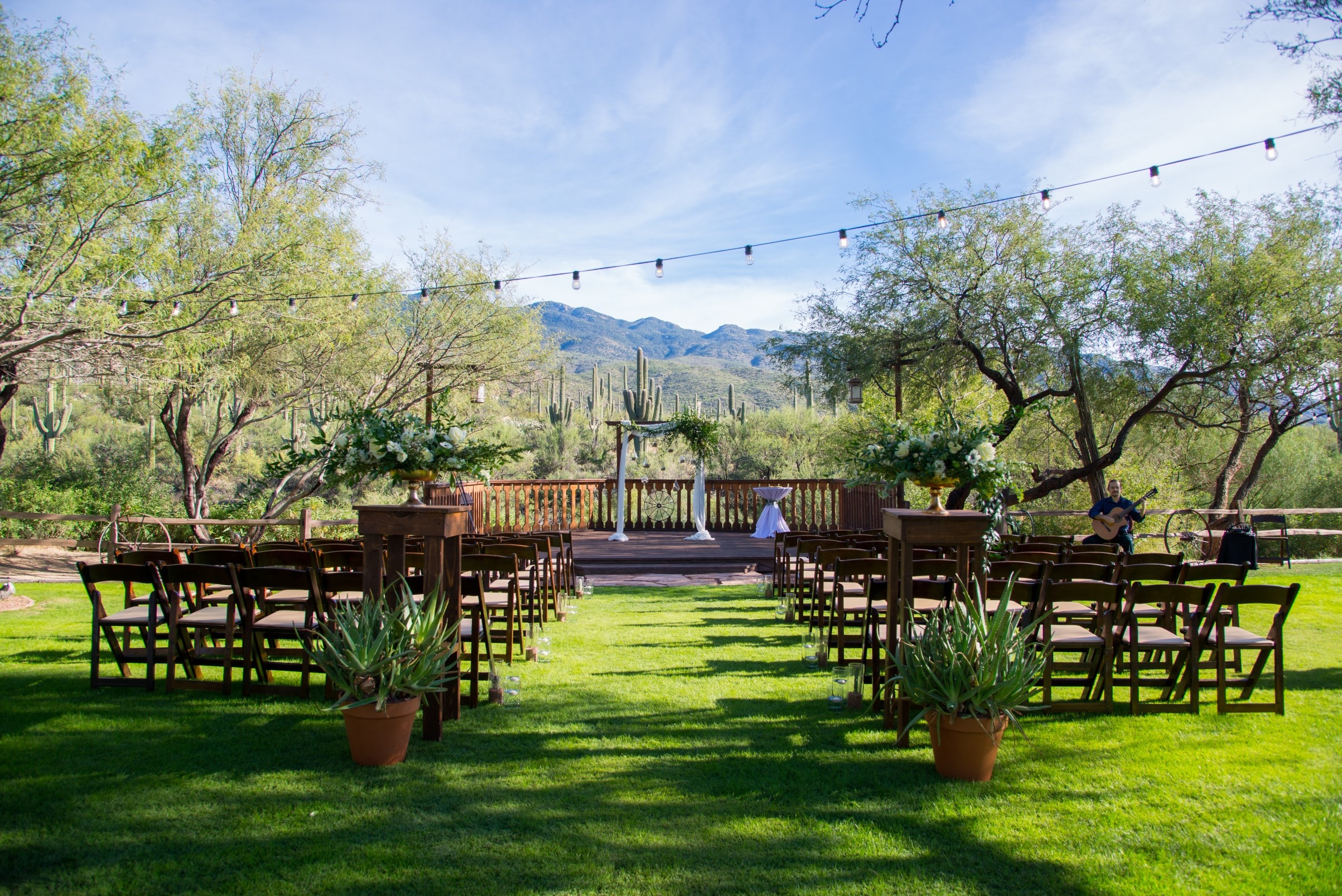 An outdoor event space with a stage, seating, and decorations, set against a backdrop of mountains and cacti.