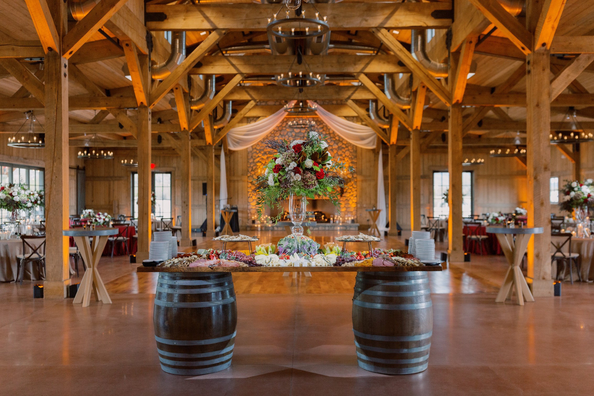 A large dining room with a table made from barrels, filled with food and flowers.