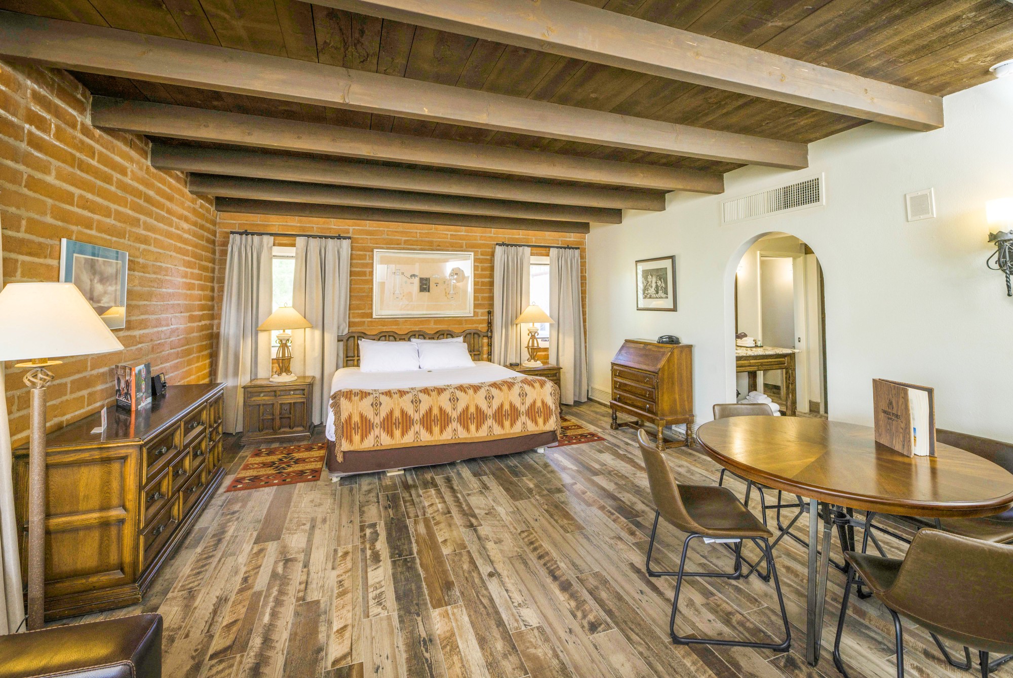 A wide view of a spacious room with a large bed, dining table, and exposed beams.