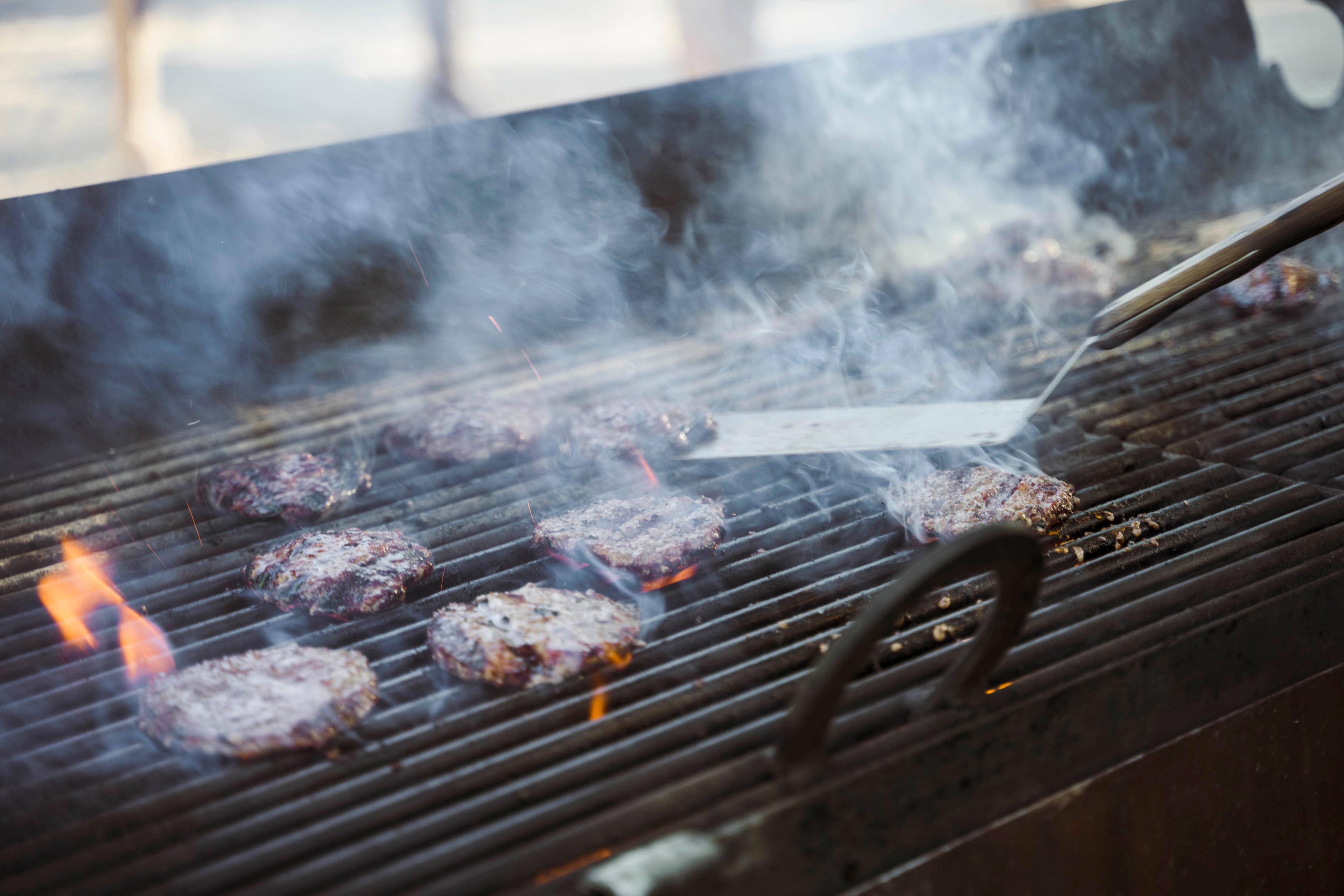 A group of burgers cooking on a grill