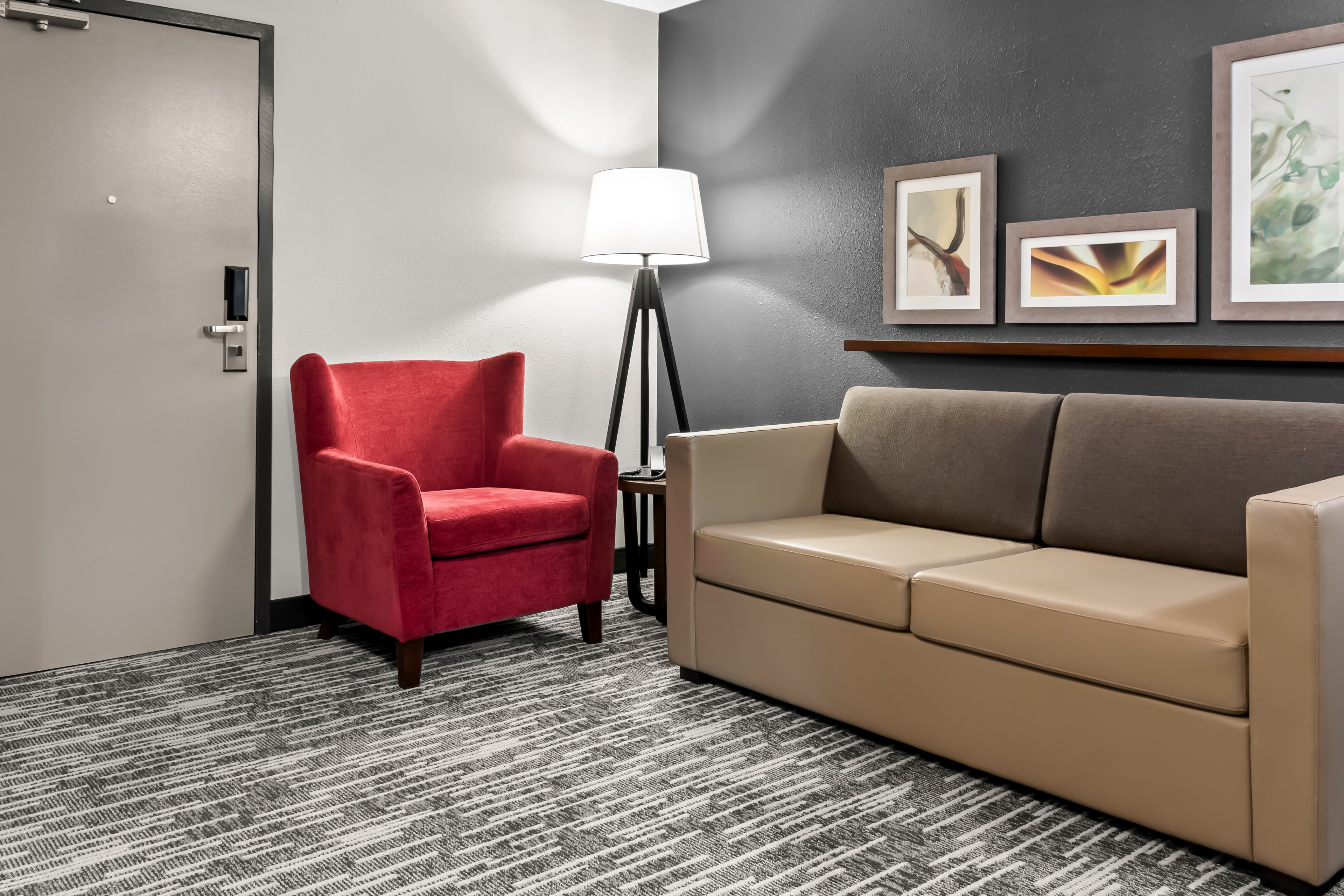A cozy room with a red armchair, beige sofa, and tall floor lamp