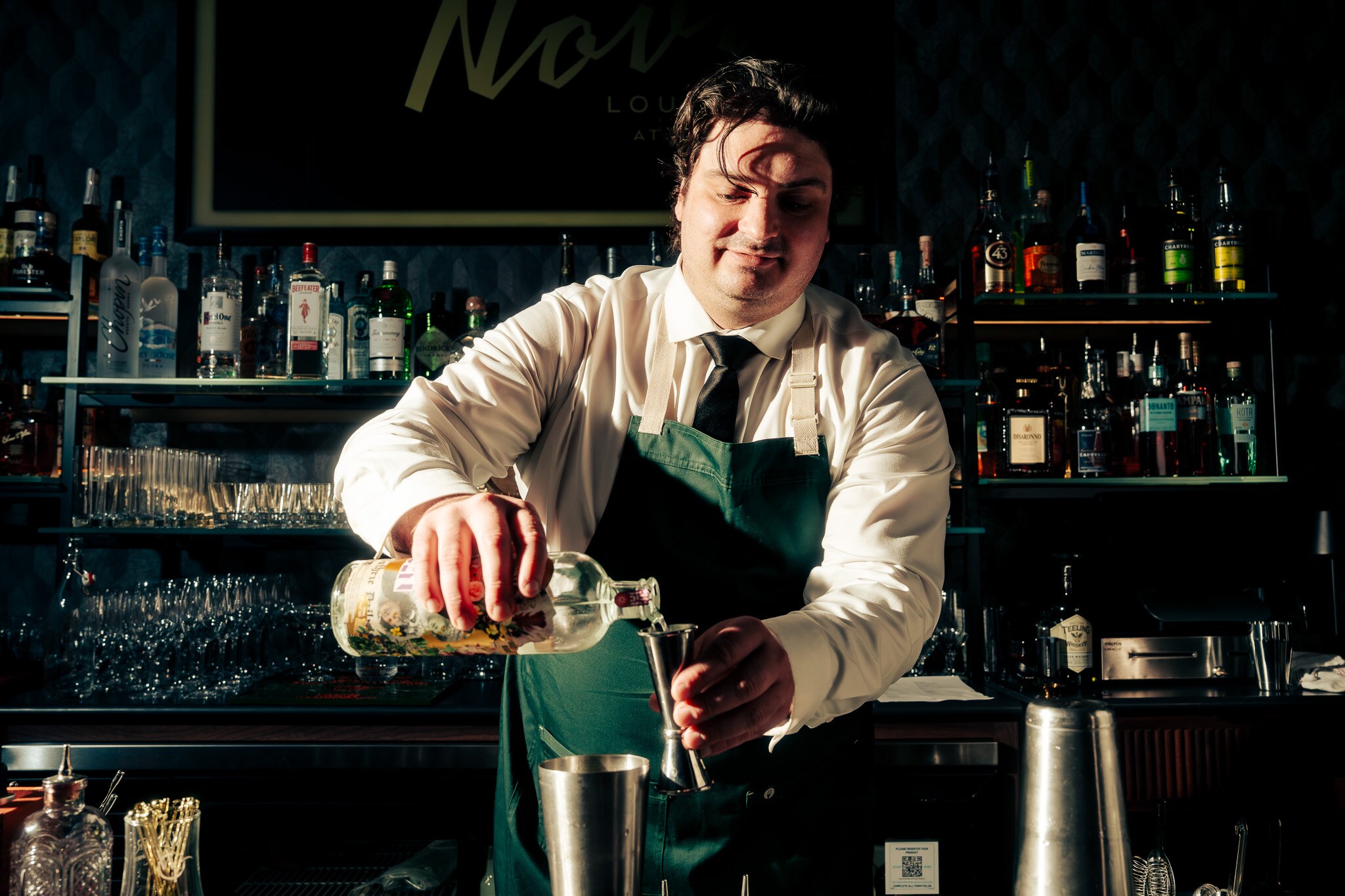 A man in a green apron is pouring a drink, Nova Lounge at Vast, Oklahoma