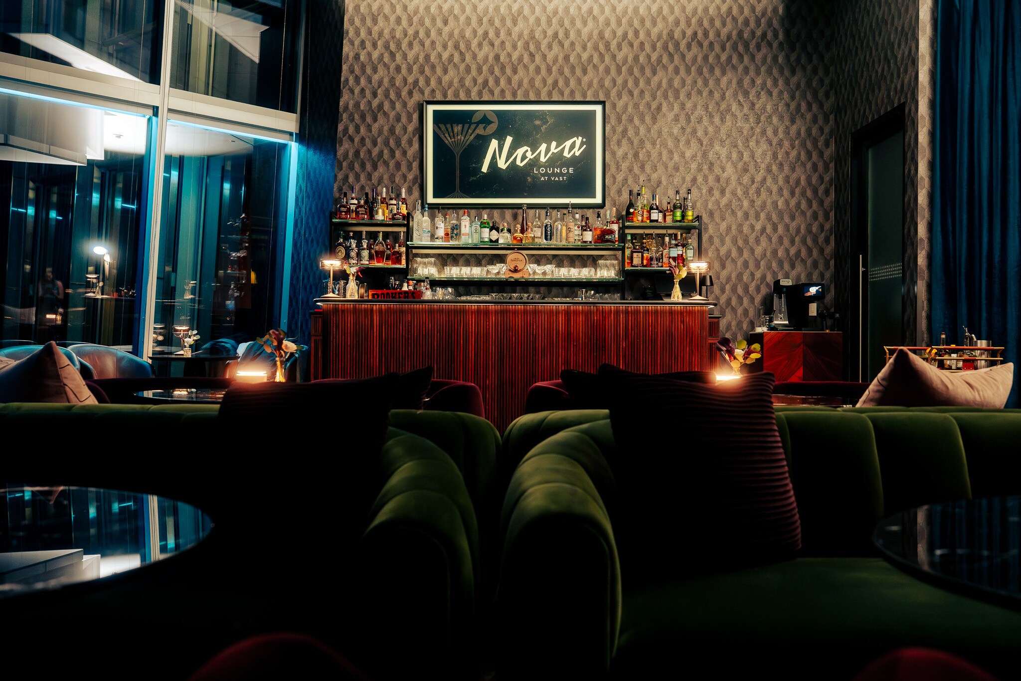 A bar with green and blue couches and a bar, Nova Lounge at Vast, Oklahoma