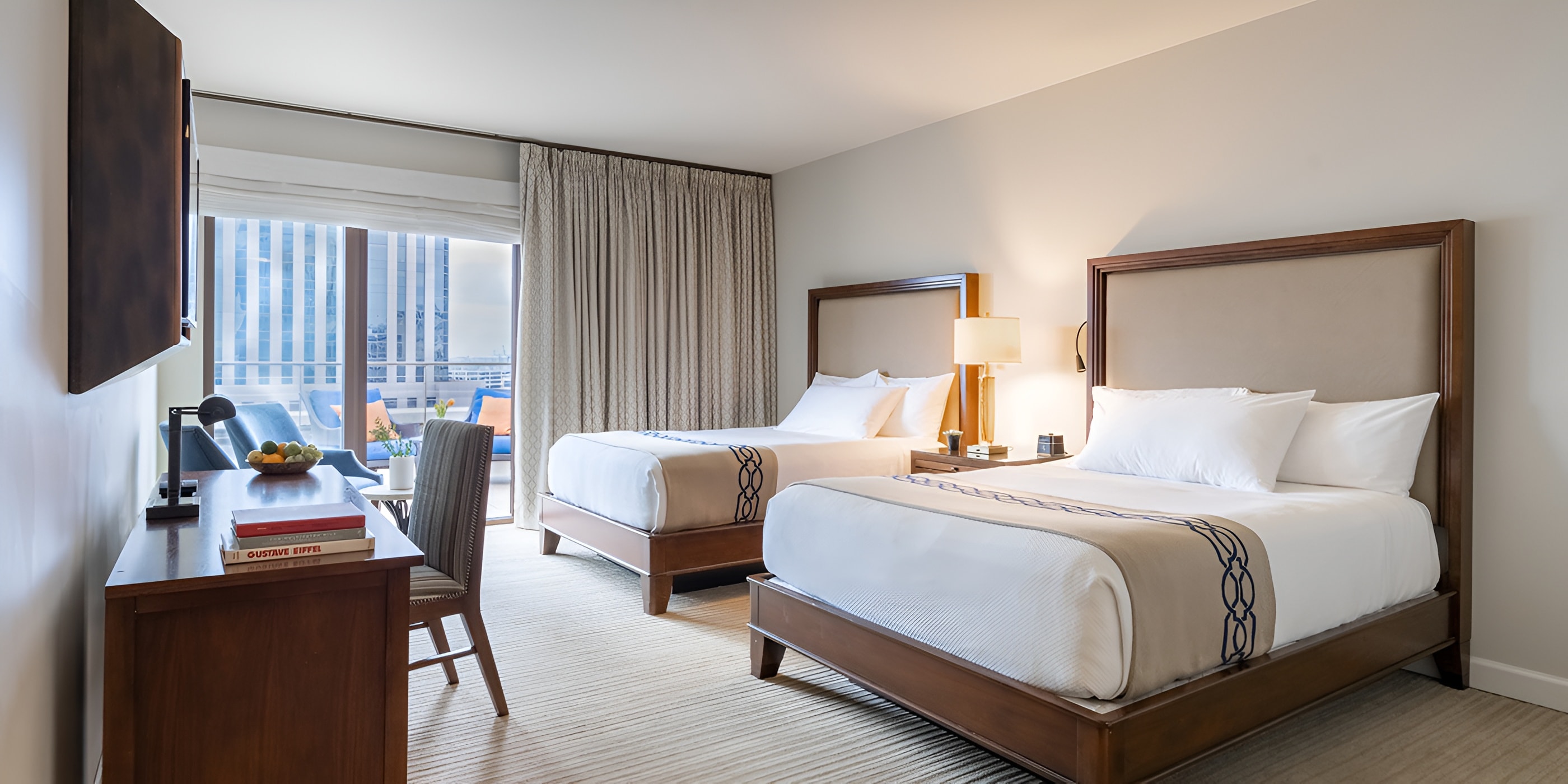 A hotel room with two beds, a nightstand, and a lamp.