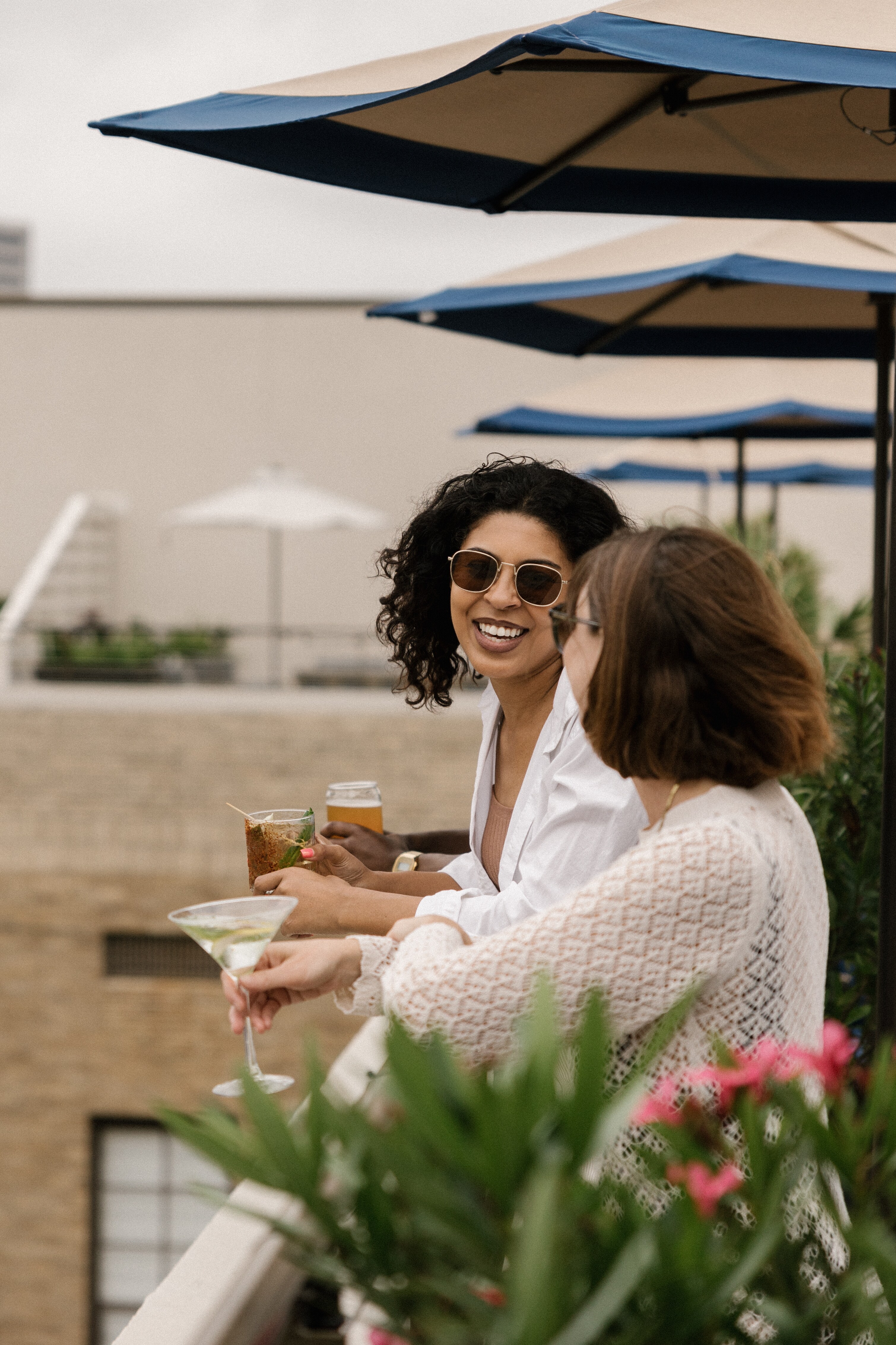 Two women enjoying drinks on a rooftop patio with city views