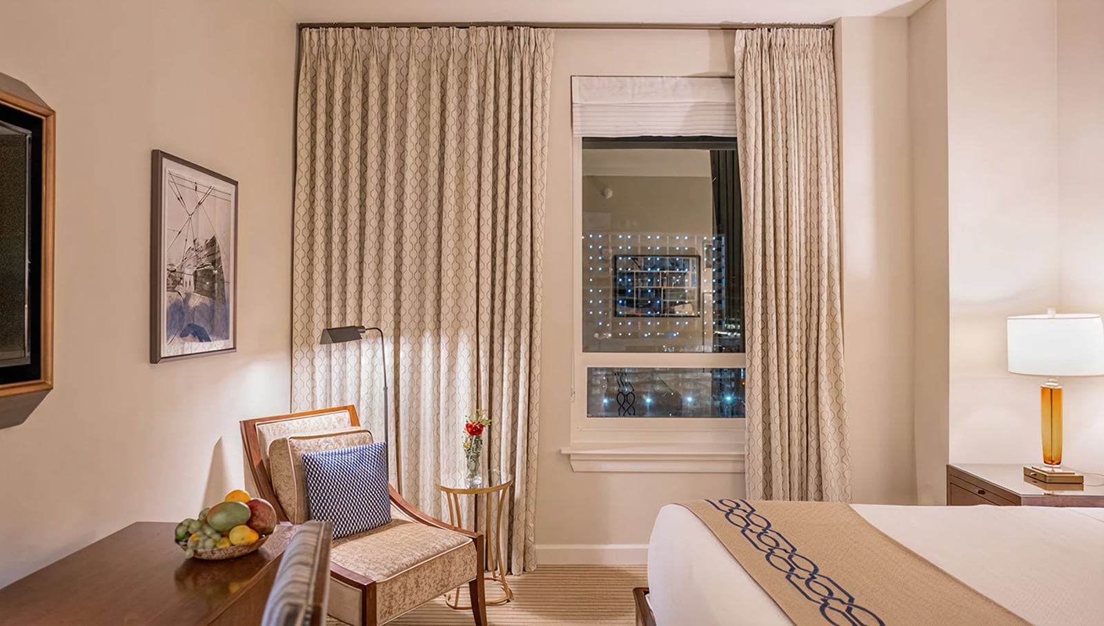 A hotel room with a bed, chair, desk, and window