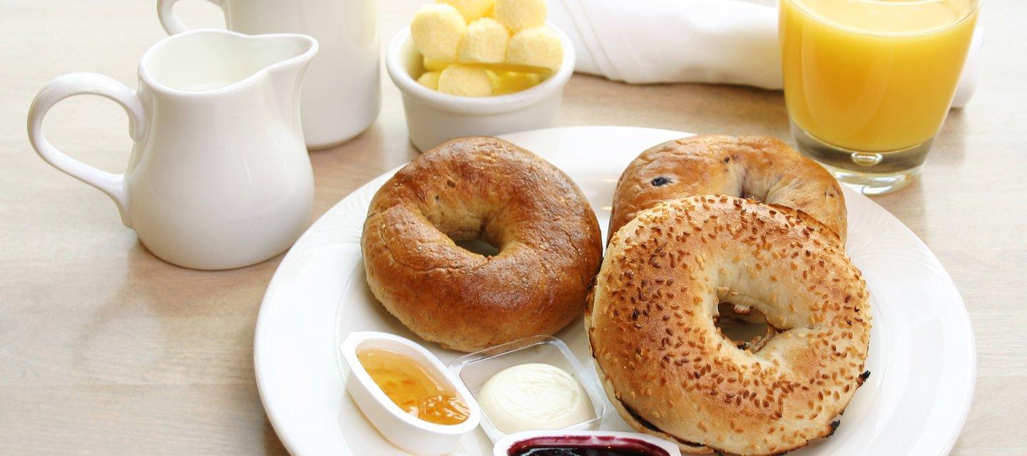 A breakfast selection of bagels, butter, jam, orange juice, and coffee and creamer at Magnolia South in Staunton Virginia at Hotel 24 South