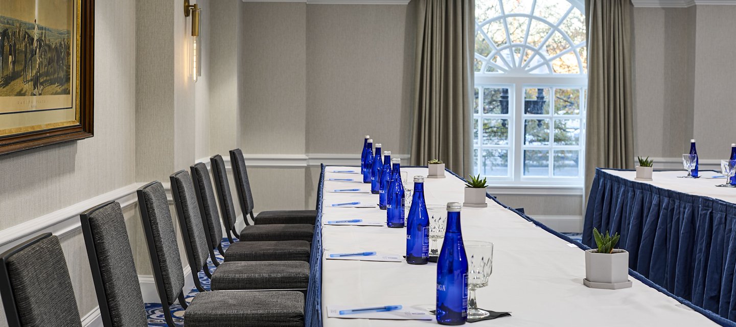 A table set up for meeting; include a water bottle and notepads