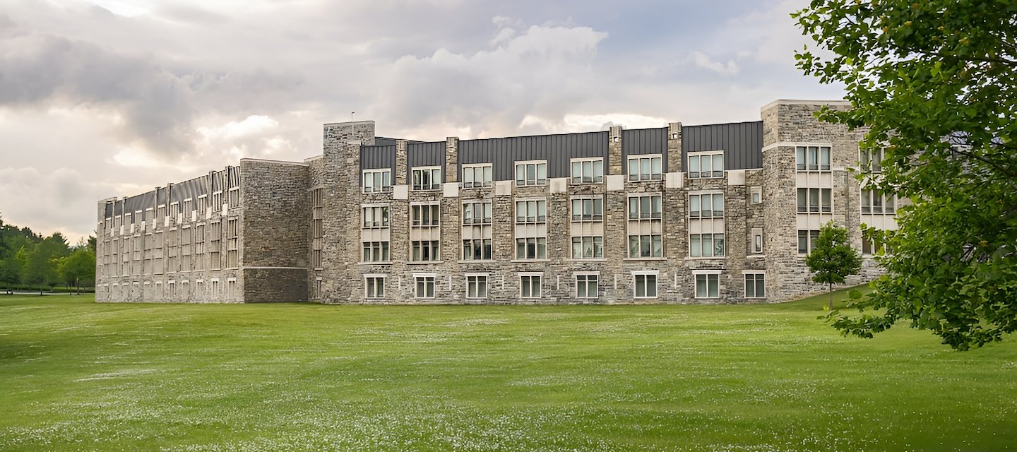 Full exterior view of The Inn at Virginia Tech with large green lawn and cloudy sky