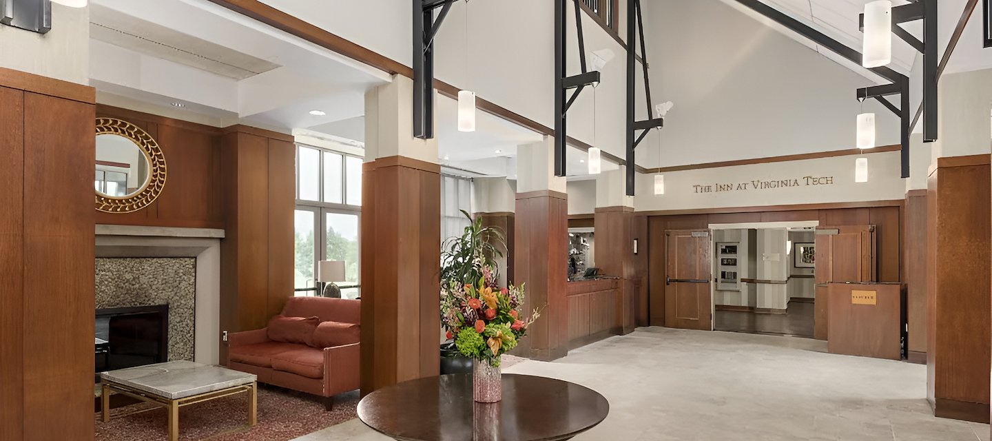 Elegant entrance area at The Inn at Virginia Tech with stone floors, wood-paneled walls, and decorative lighting