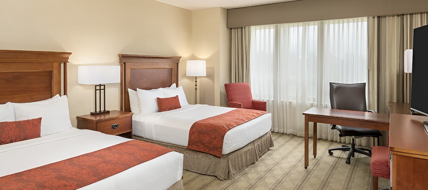 Elegant two-bed guest room with plush bedding, desk, and seating area at The Inn at Virginia Tech and Skelton Conference Center.