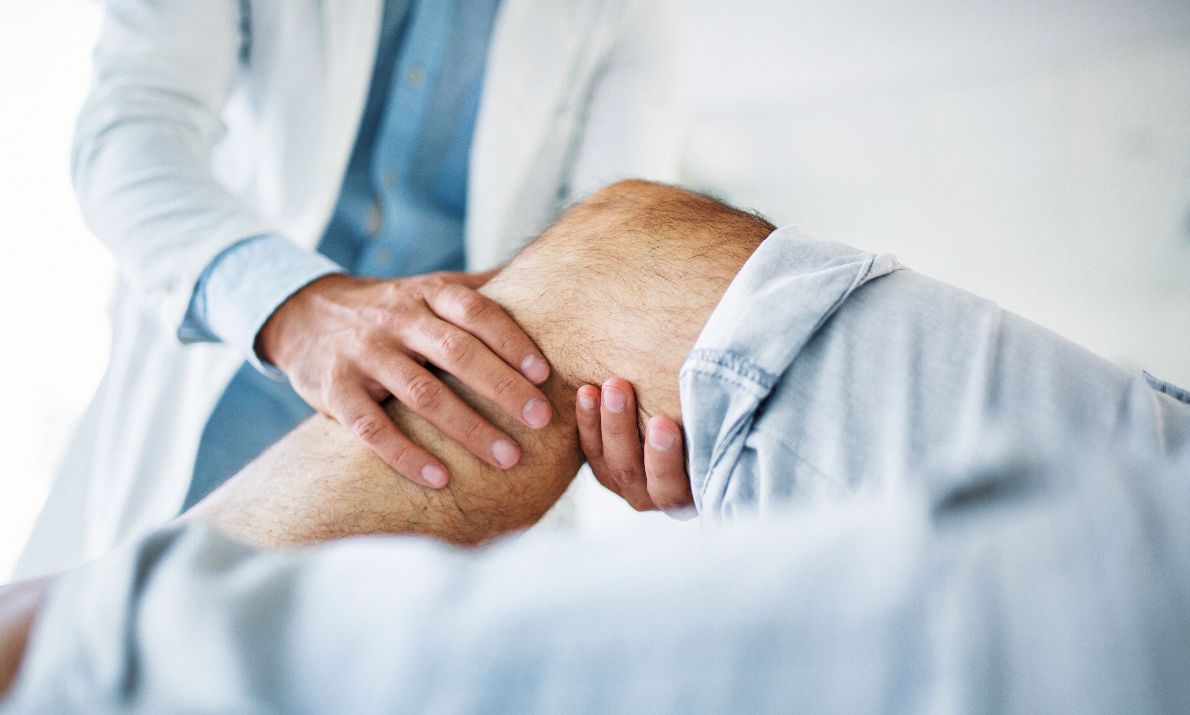 A healthcare professional examines a patient's knee at Brij Medical Centre.