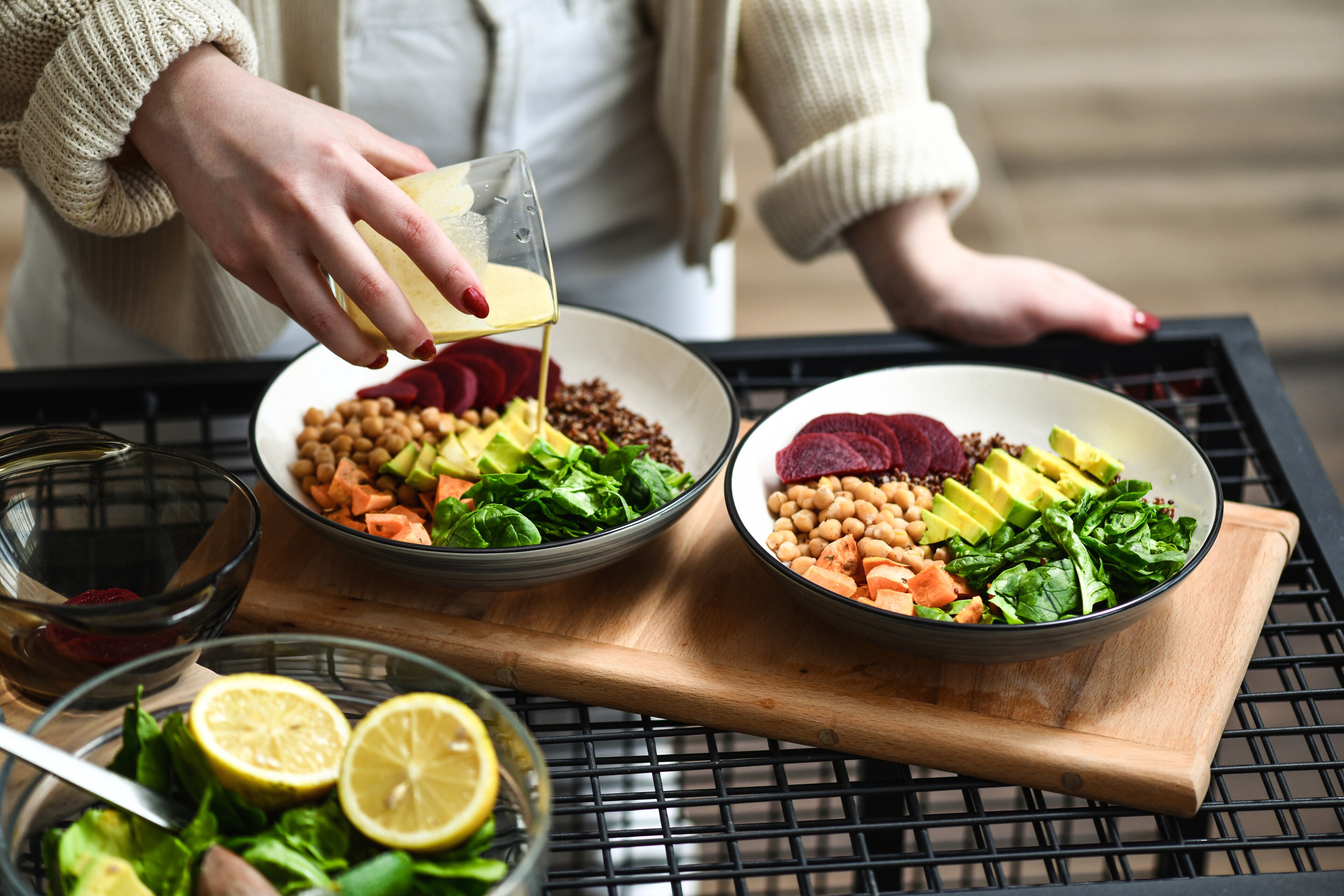 Female Preparing Aesthetically Pleasing Salad Bowls Adding Dressing on Top To Tie Flavors Together.