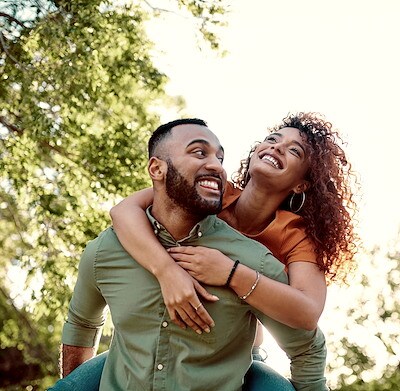 Shot of a young man giving his girlfriend a piggyback ride outdoors