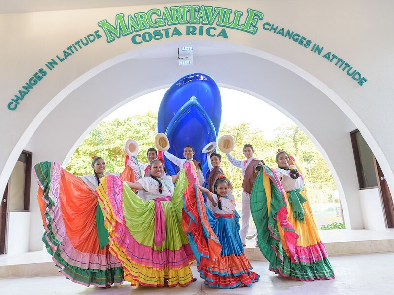 A group of people in colorful dresses dancing under a archway
