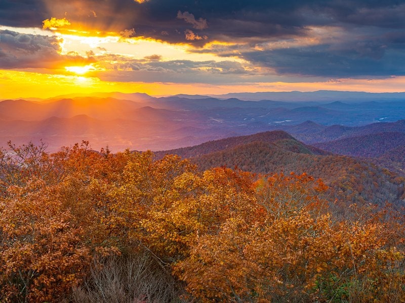 A sunset over mountains with trees and bushes