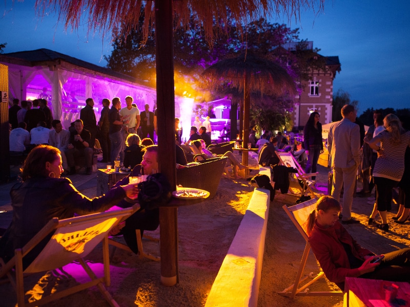 A group of people sitting at tables outside at night
