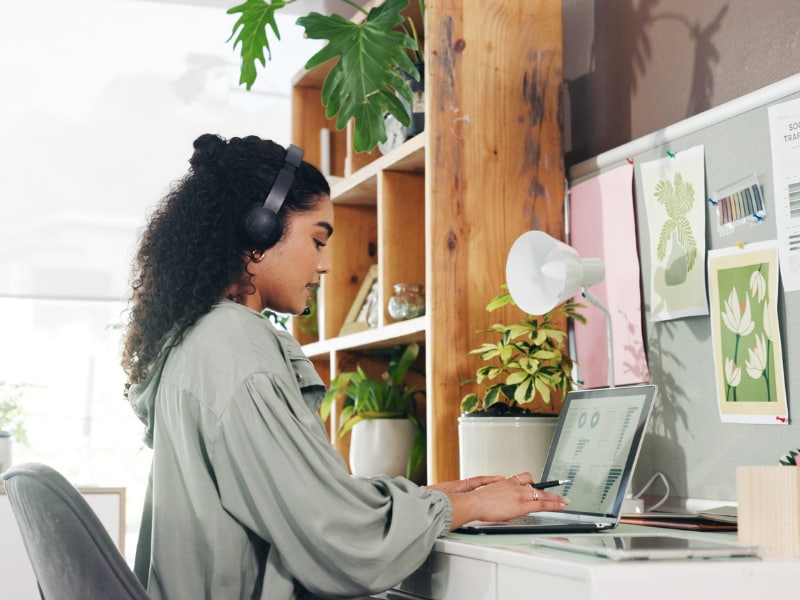 Home office workspace with a person wearing headphones and working on a laptop.