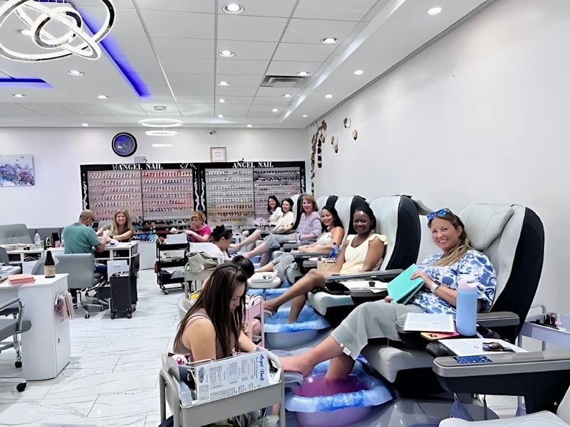 A group of people sitting in chairs in a nail salon