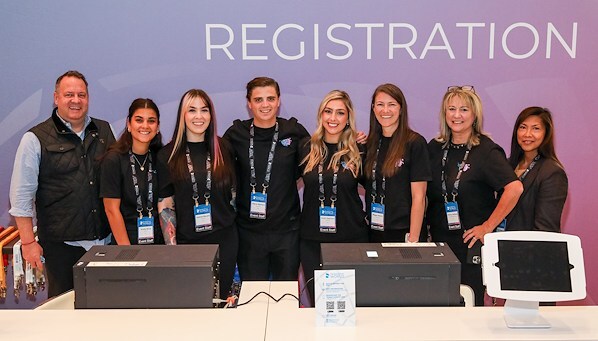 A group of employees of EMC Meeting & Events, Sea Girt, New Jersey standing behind a registration desk in a professional setting.