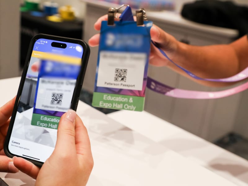 Event attendee scanning QR code badge for check-in at conference registration desk